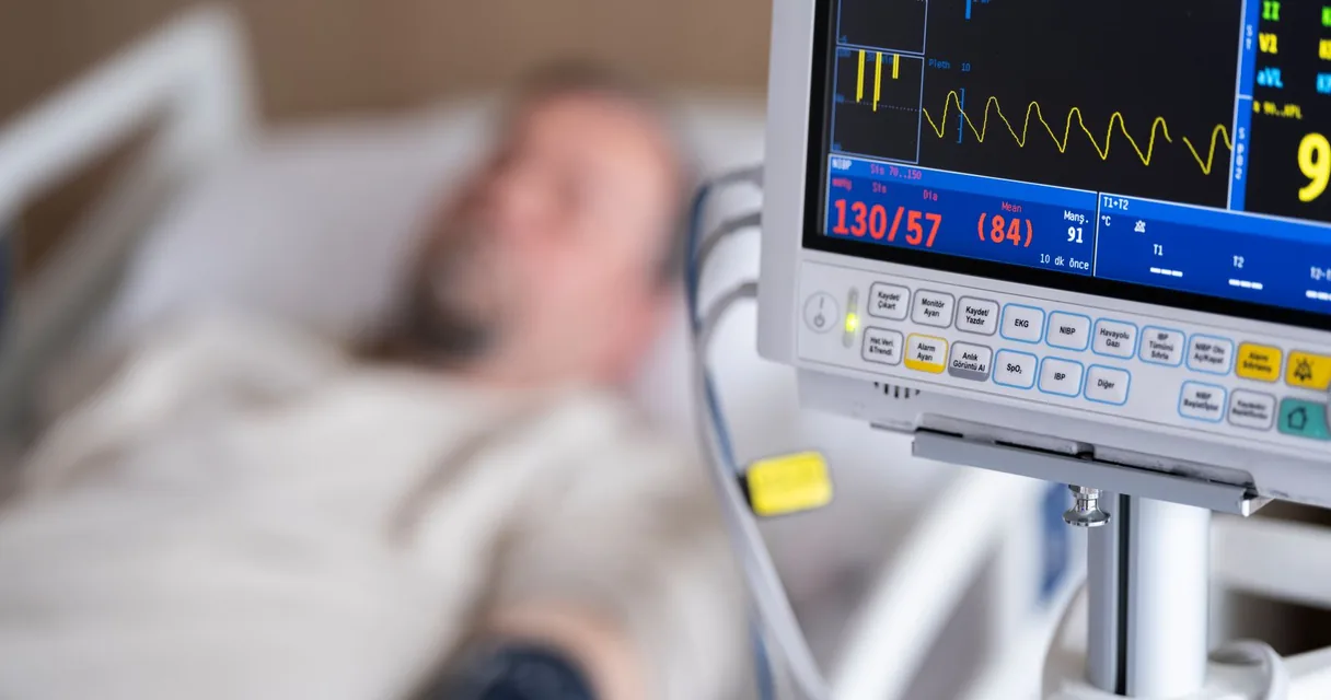 Paciente em leito de terapia intensiva ao lado de um monitor